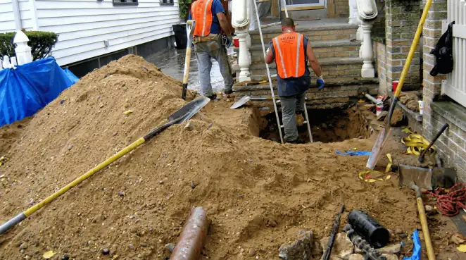 Contractors performing foundation protection and exterior drainage excavation near residential home steps in Oklahoma City, OK