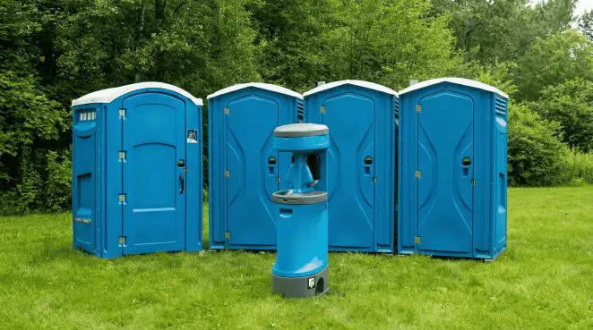 Four blue portable toilets and a matching hand washing station on grass near trees, a common sight at local outdoor events in Oklahoma City, OK