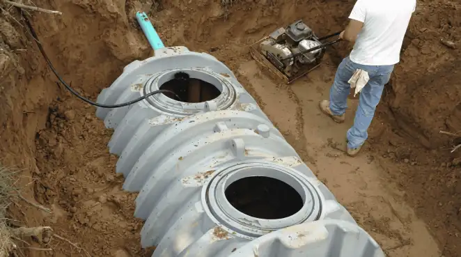 Septic tank installation showing a technician compacting soil around a new poly septic tank in an excavation pit in Oklahoma City, OK